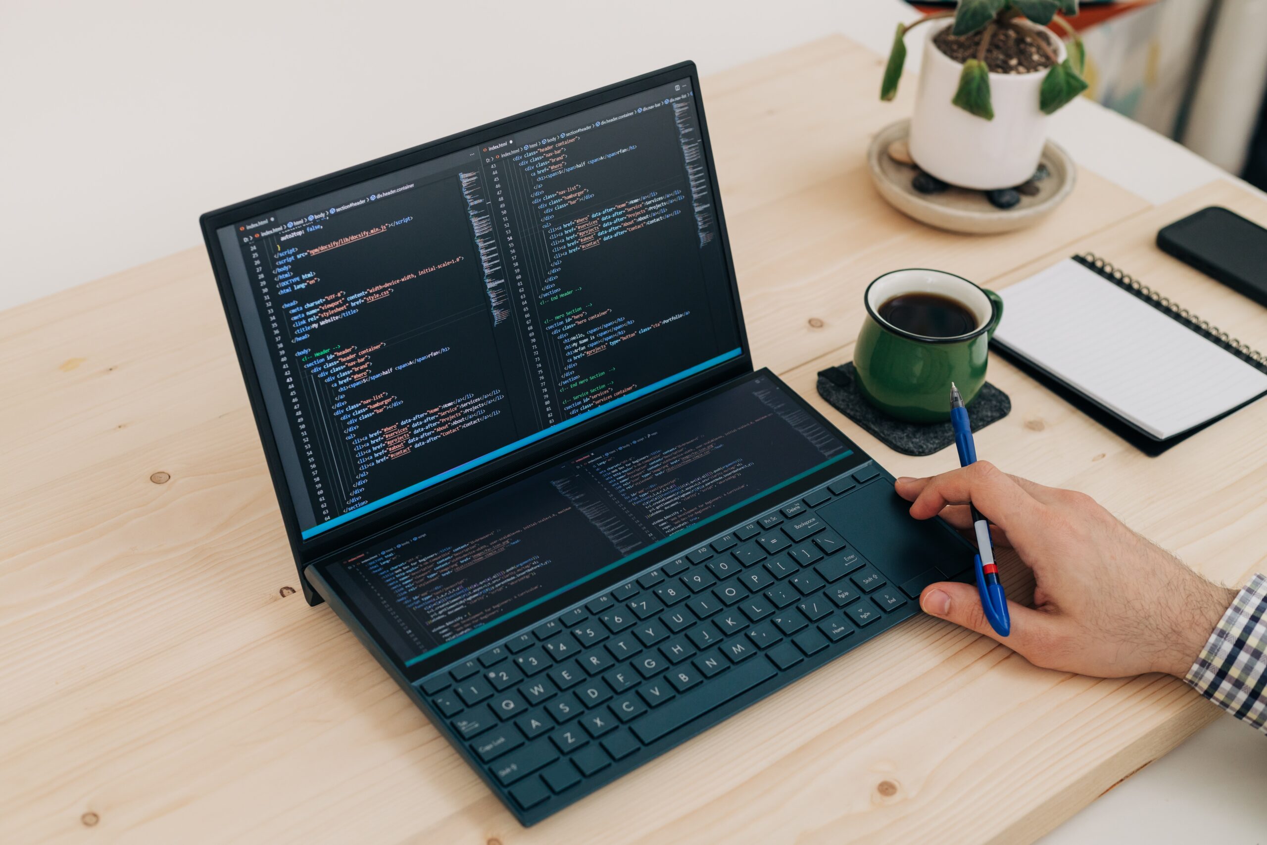 A person writing code on a laptop on a desk