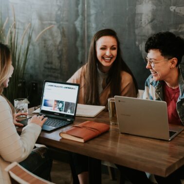College students sitting and laughing with open laptops