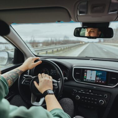 Man in a hat driving a car with his hand on the horn