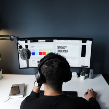 man with headphones sitting in front of computer doing freelance work