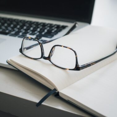 Laptop, notebook, and glasses sitting on table