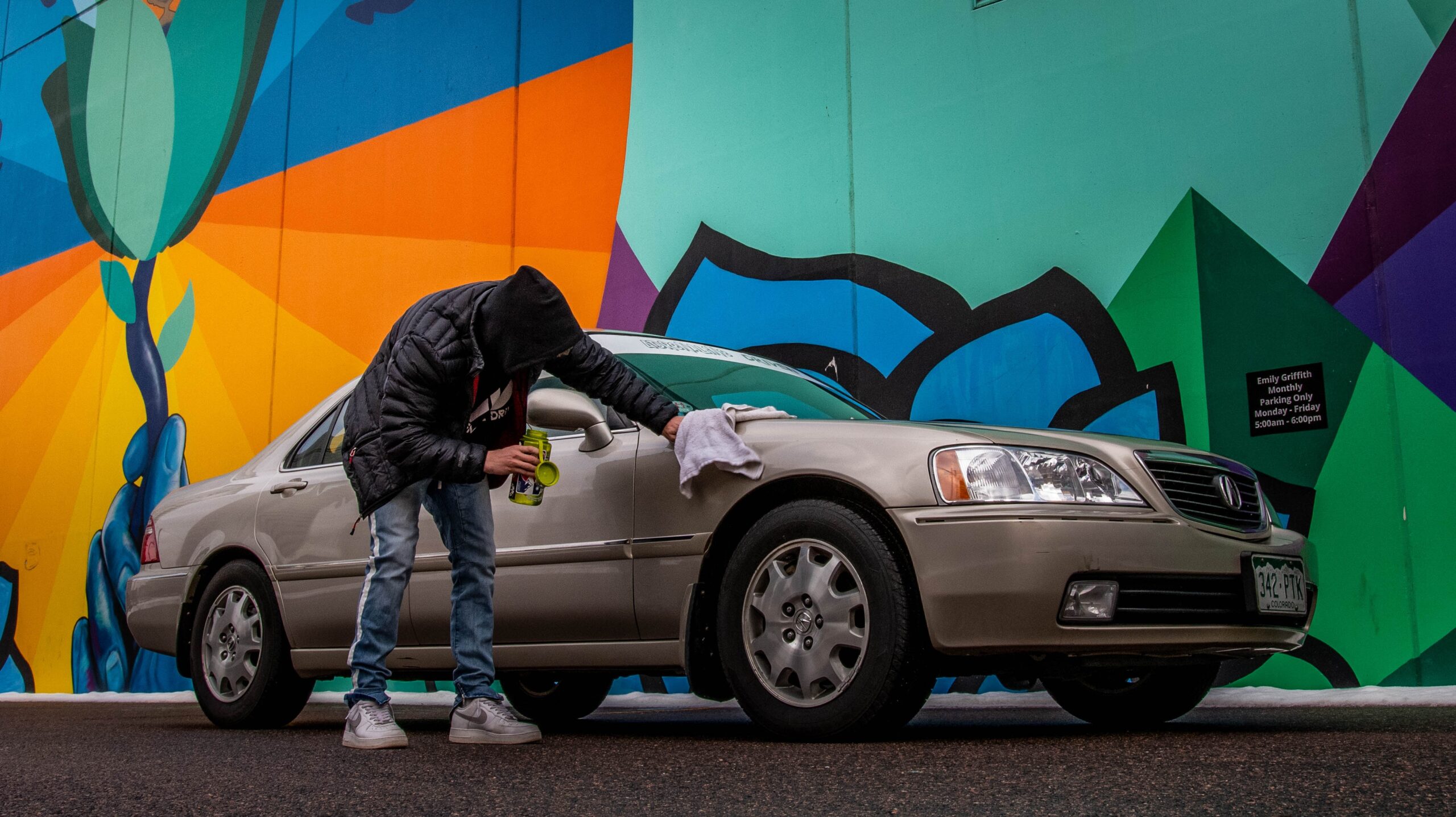 Man in black jacket detailing a used car to sell