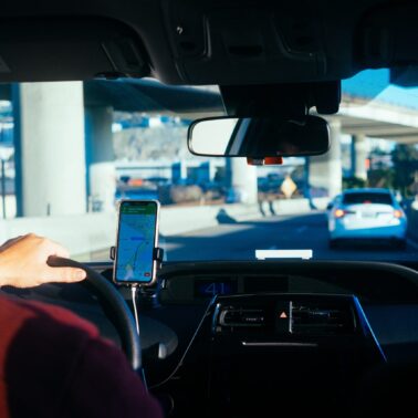 person with iphone on holder inside a car and driving