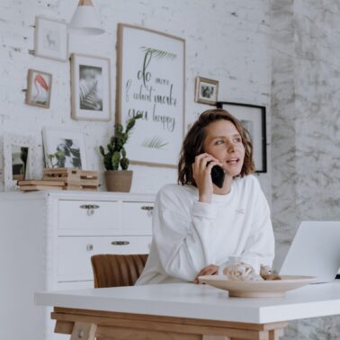 Woman sitting at desk in front of laptop talking on her phone