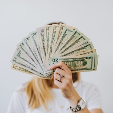 person holding handful of money in front of their face